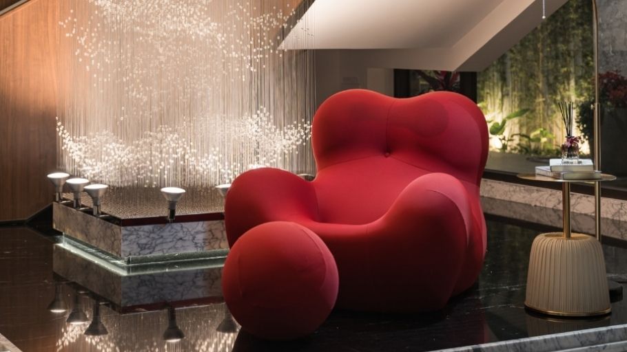 Chi tiết nội thất cao cấp: ghế lounge đỏ nổi bật bên dưới thác đèn pha lê dài, mang đến không gian sống nghệ thuật và đầy cảm xúc tại SEN Villa
