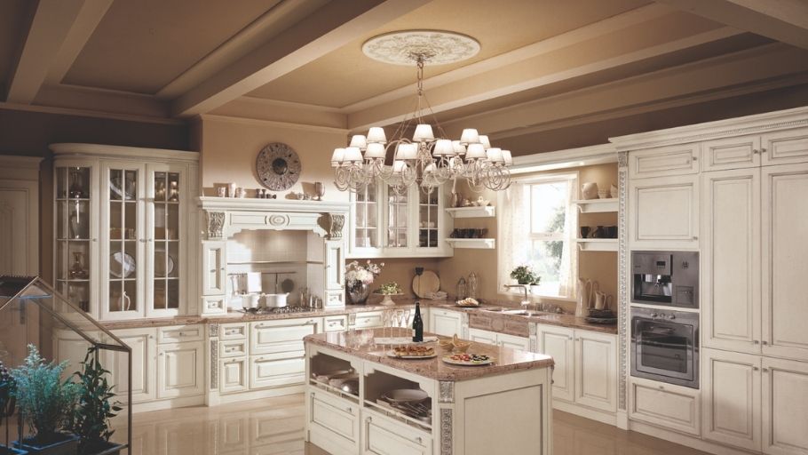 Bếp mở rộng lớn, tủ trắng viền vàng, đảo bếp đá và đèn chùm