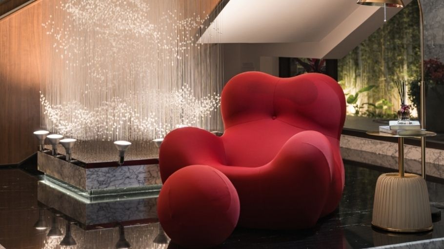 Chi tiết nội thất cao cấp: ghế lounge đỏ nổi bật bên dưới thác đèn pha lê dài, mang đến không gian sống nghệ thuật và đầy cảm xúc tại SEN Villa