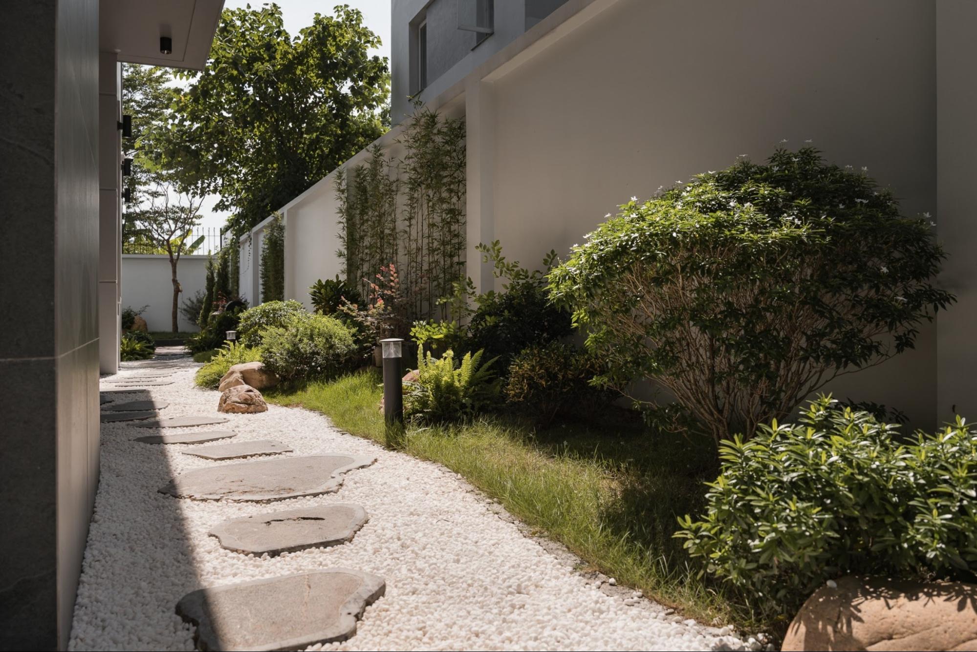 A natural-stone paved path over white gravel leads through the lush tropical garden of a Modern-style garden villa.