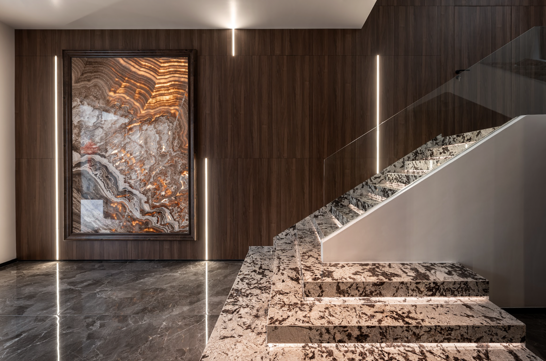 The staircase uses natural stone, refined railings, and a lighting system to create a luxurious focal point.
