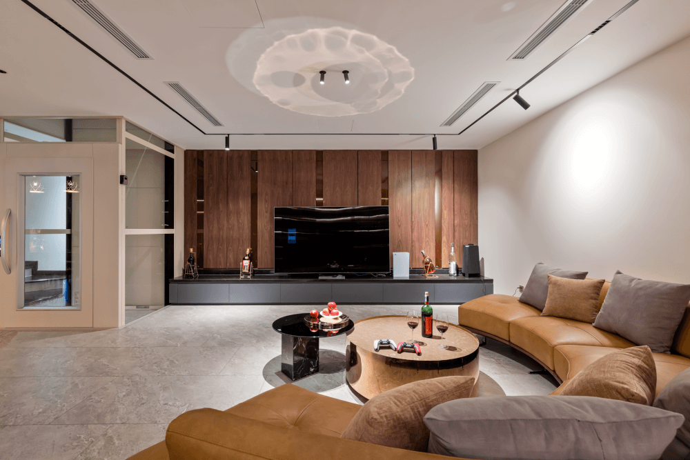 Sofa da bò uốn cong và vách ốp gỗ trầm ấm tạo nên điểm nhấn sang trọng cho phòng khách biệt thự Vinhomes Green Bay. (Nguồn ảnh: Internet)